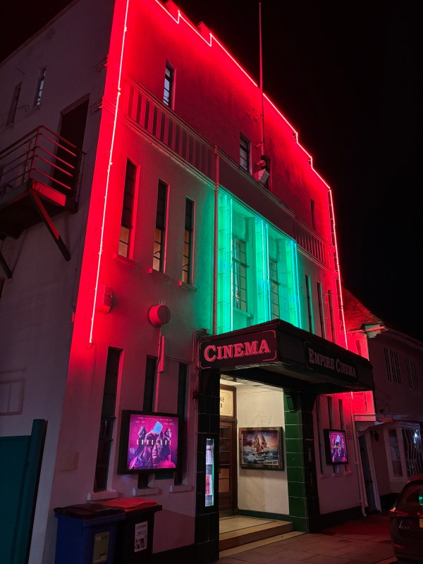 A cinema front lit with neon lights