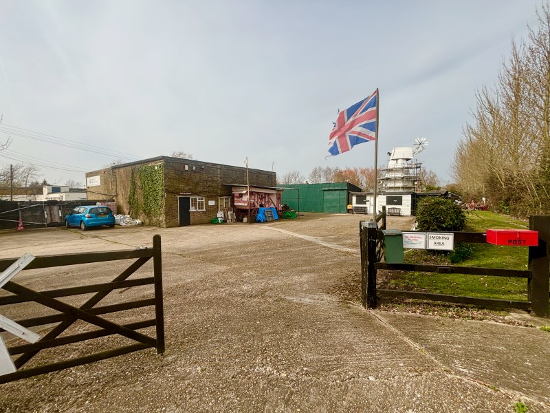 A white windmill past a gated entrance.